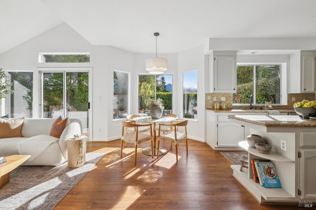 kitchen with dark wood-type flooring, stone counters, tasteful backsplash, decorative light fixtures, and white cabinetry