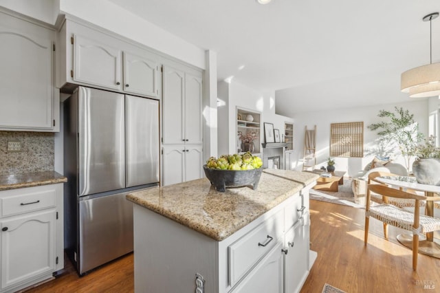 kitchen featuring backsplash, white cabinets, a center island, light hardwood / wood-style floors, and stainless steel refrigerator