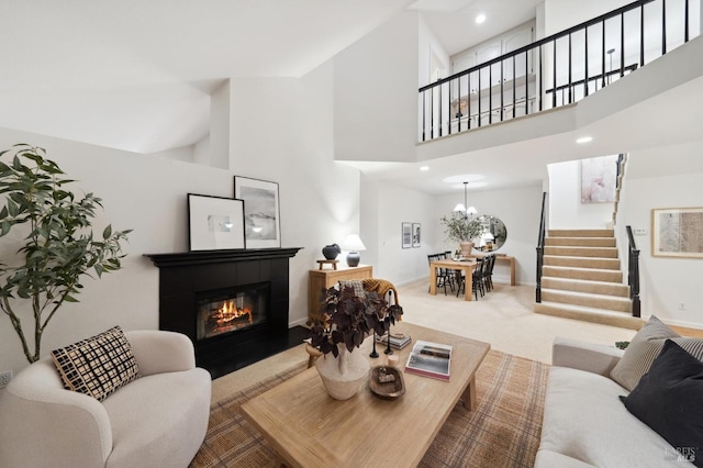 carpeted living room featuring a tile fireplace and a towering ceiling