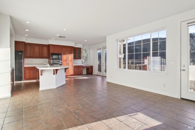 unfurnished living room with a glass covered fireplace, visible vents, and baseboards
