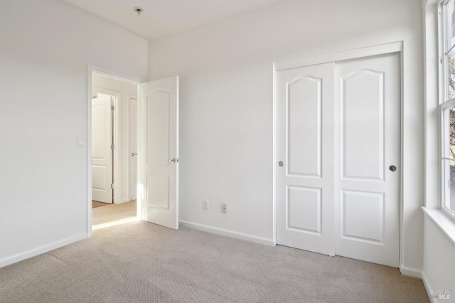 unfurnished bedroom featuring light carpet and a closet