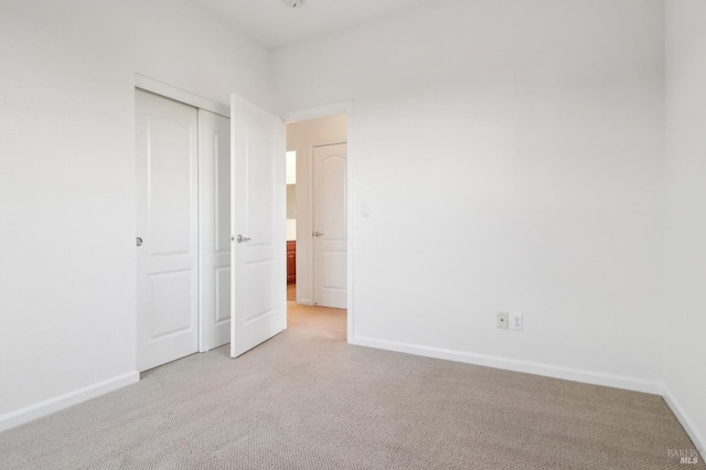 unfurnished bedroom with light carpet and a closet