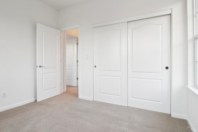 unfurnished bedroom with light colored carpet and a closet