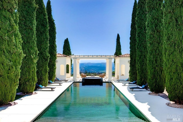 view of swimming pool with a pool with connected hot tub and a pergola