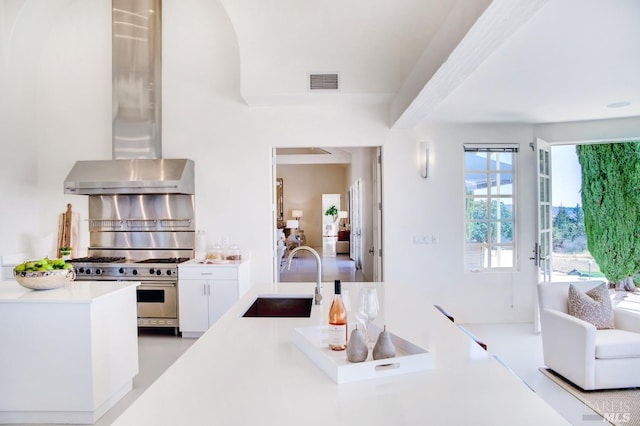 kitchen with a sink, visible vents, white cabinets, light countertops, and high end range