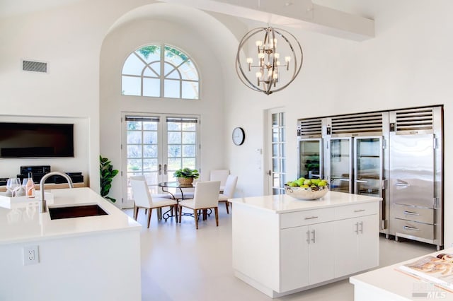 kitchen with hanging light fixtures, french doors, a sink, and a kitchen island with sink