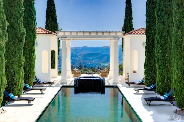 outdoor pool with a patio, a mountain view, and a pergola