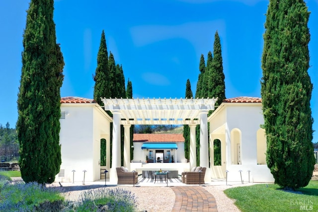 rear view of property featuring a patio area, stucco siding, a tiled roof, and a pergola