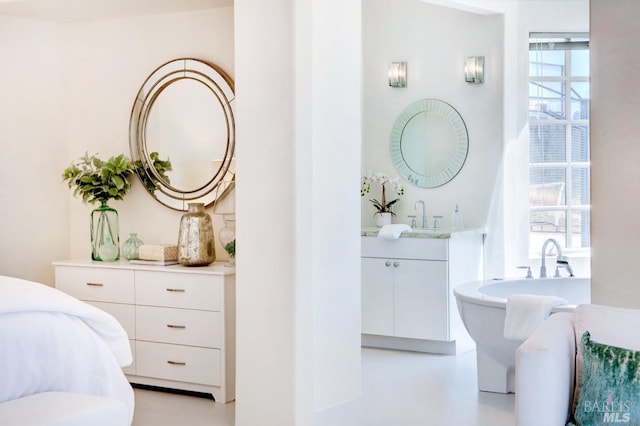 full bathroom with concrete floors, vanity, and a freestanding bath