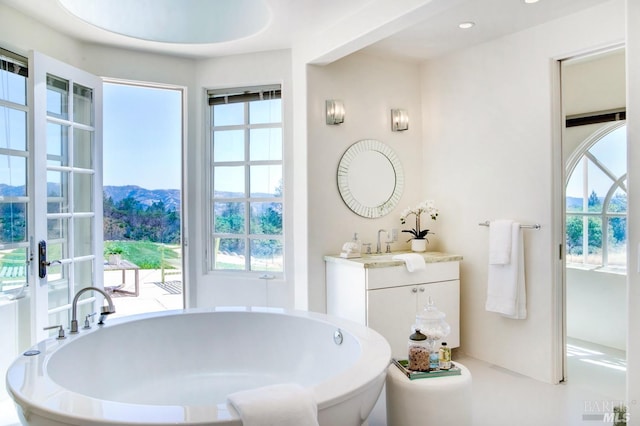 bathroom with a soaking tub, vanity, and recessed lighting