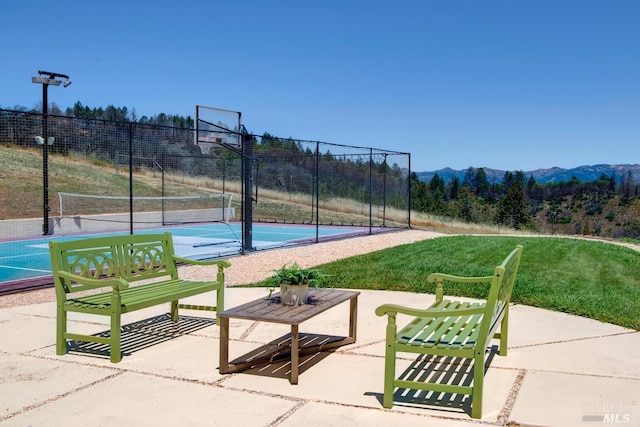 view of basketball court with a lawn, a tennis court, fence, community basketball court, and a mountain view