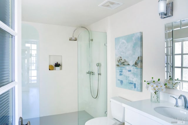 bathroom featuring toilet, walk in shower, vanity, and visible vents