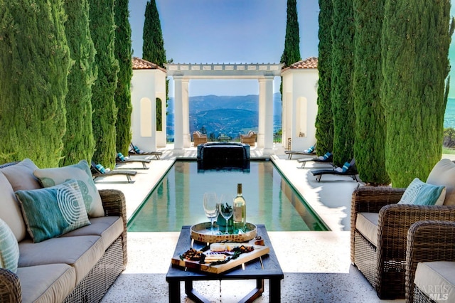 outdoor pool featuring a mountain view, an outdoor living space, and a patio