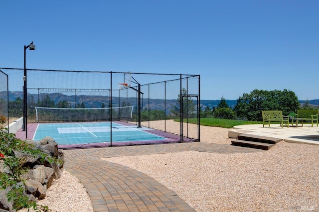 view of basketball court featuring community basketball court, a mountain view, a tennis court, and fence