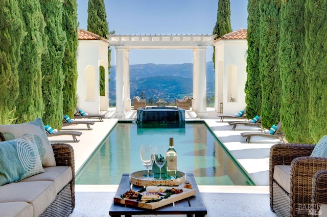 view of pool with a pool with connected hot tub, a patio, and a mountain view