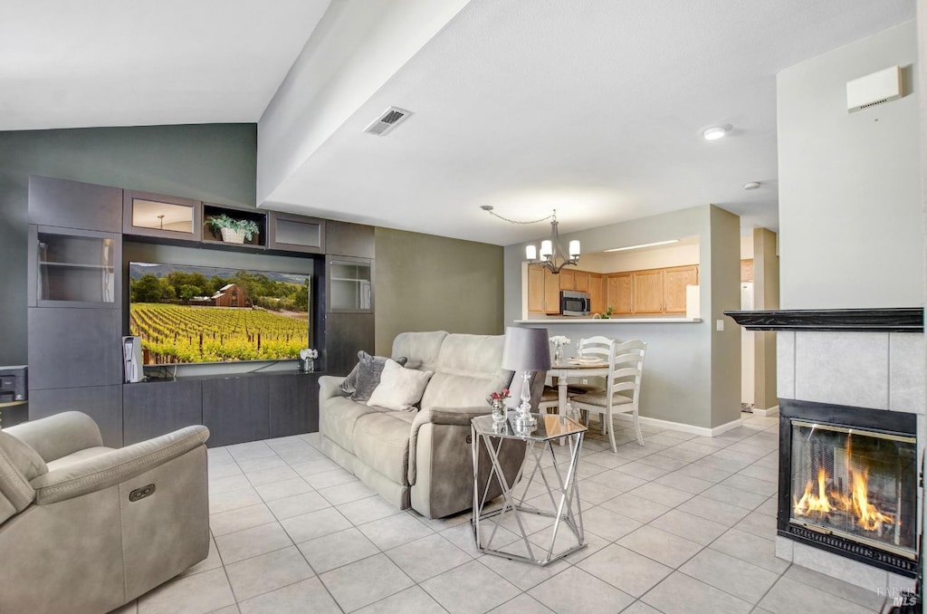 living room featuring a tile fireplace, built in shelves, vaulted ceiling, and light tile patterned flooring