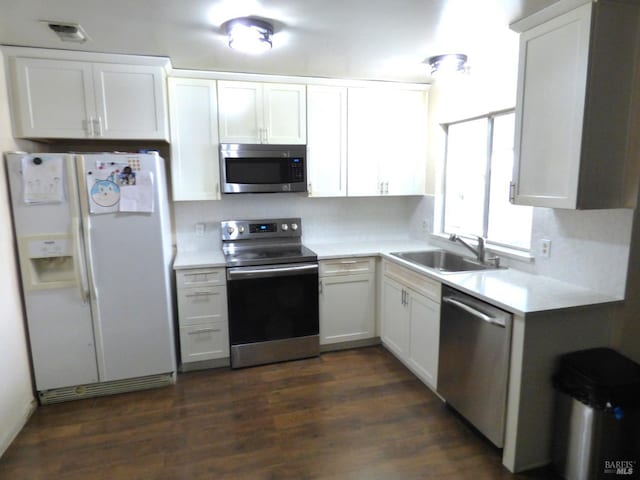 kitchen with sink, dark wood-type flooring, stainless steel appliances, and white cabinets