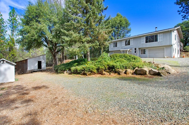 view of front of home featuring a garage, driveway, a storage shed, and an outbuilding