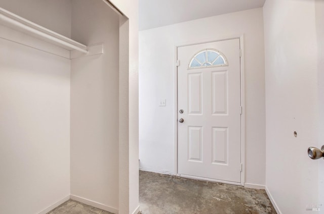 foyer entrance with baseboards and unfinished concrete flooring