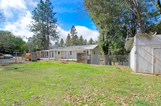 back of house featuring a storage shed, fence, a lawn, and an outdoor structure