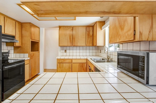 kitchen with stainless steel microwave, black range with electric cooktop, a glass covered fireplace, and tile counters