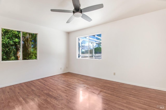 spare room featuring ceiling fan, baseboards, and wood finished floors