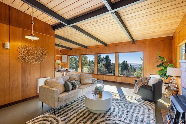 living room featuring beam ceiling, concrete floors, a wealth of natural light, and wood walls