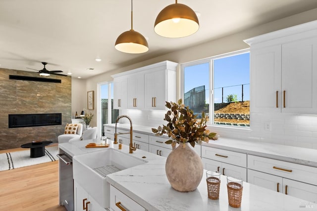 kitchen with white cabinetry, hanging light fixtures, decorative backsplash, and light hardwood / wood-style flooring