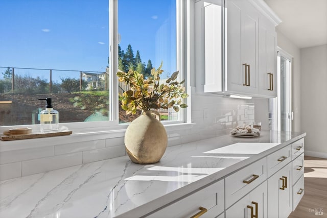 kitchen featuring light stone counters, backsplash, and white cabinetry