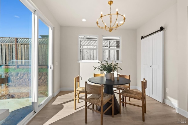 dining area featuring plenty of natural light, a barn door, a chandelier, and wood-type flooring