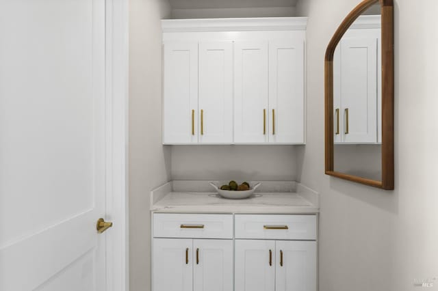 bar featuring white cabinetry and light stone countertops