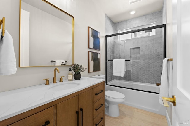 full bathroom with enclosed tub / shower combo, vanity, and toilet