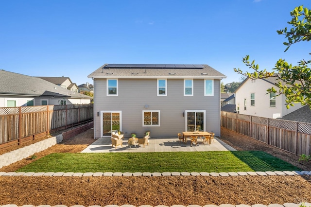 rear view of house featuring a yard, a patio, and solar panels