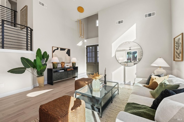 living room with light wood-type flooring and a high ceiling