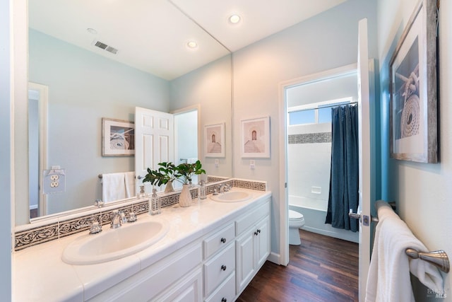 full bathroom featuring hardwood / wood-style flooring, vanity, shower / bath combo, and toilet