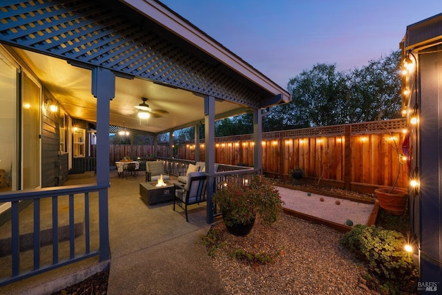 patio terrace at dusk with ceiling fan and an outdoor living space with a fire pit