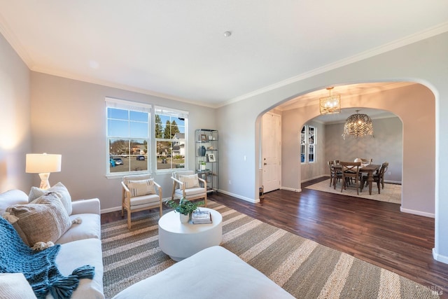 living room with crown molding, dark wood-type flooring, and a chandelier