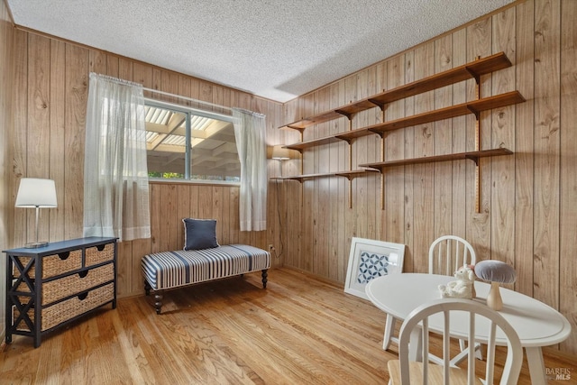 living area with wood walls, a textured ceiling, and light hardwood / wood-style flooring