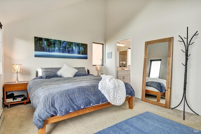 bedroom with high vaulted ceiling, a baseboard radiator, light carpet, and ensuite bath