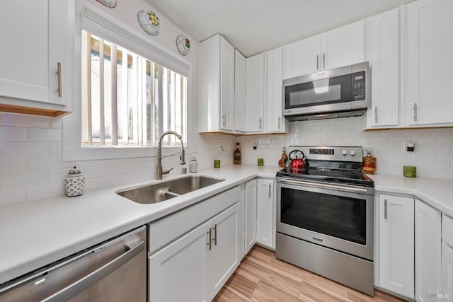 kitchen featuring sink, stainless steel appliances, backsplash, light hardwood / wood-style floors, and white cabinets