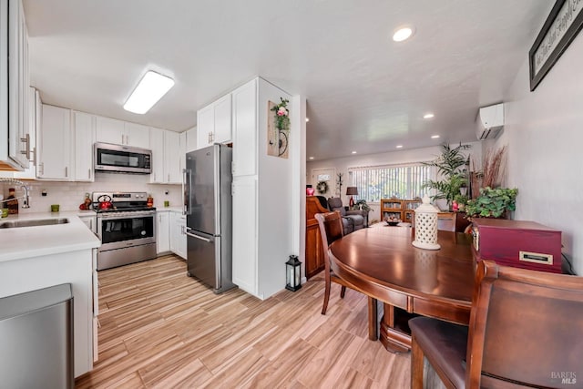 kitchen featuring white cabinets, sink, decorative backsplash, stainless steel appliances, and a wall unit AC