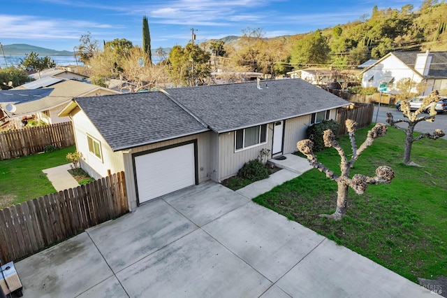 ranch-style home with a mountain view, a front lawn, and a garage