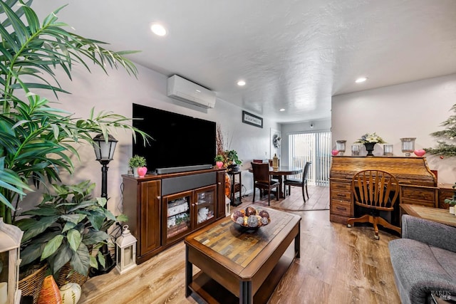 living room with a wall mounted air conditioner and light hardwood / wood-style flooring