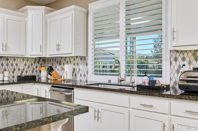 kitchen with tasteful backsplash, white cabinetry, sink, and dark stone counters