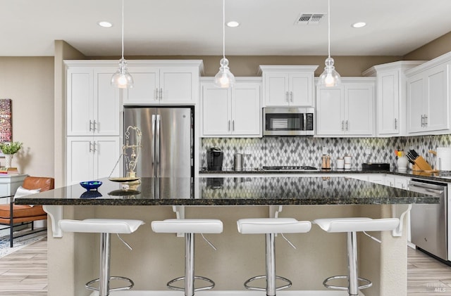 kitchen featuring hanging light fixtures, a center island, stainless steel appliances, and tasteful backsplash