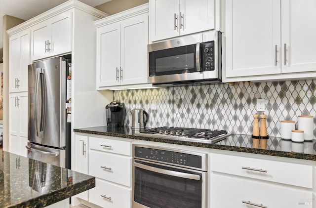 kitchen featuring decorative backsplash, stainless steel appliances, white cabinetry, and dark stone counters