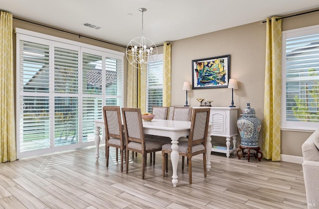 dining area with light hardwood / wood-style flooring, a wealth of natural light, and a notable chandelier