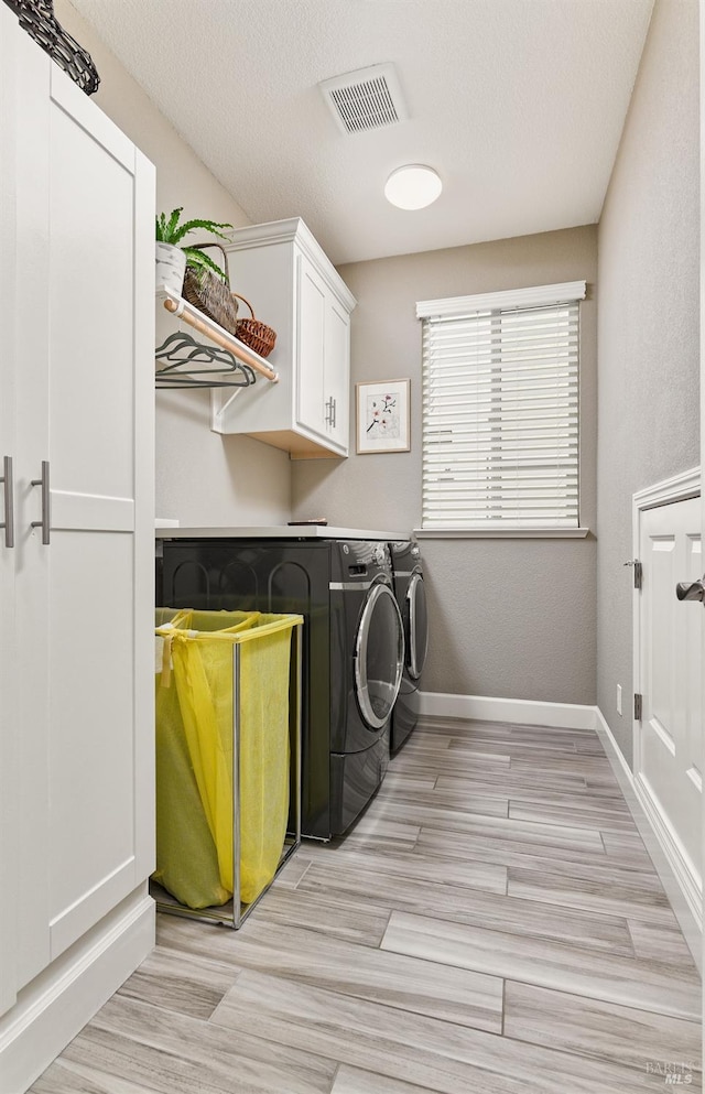 laundry area featuring light hardwood / wood-style floors, cabinets, independent washer and dryer, and a textured ceiling