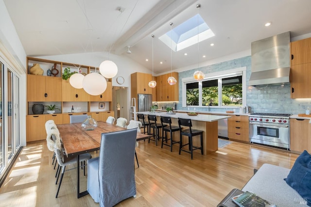 dining area with light hardwood / wood-style floors, lofted ceiling with skylight, and sink