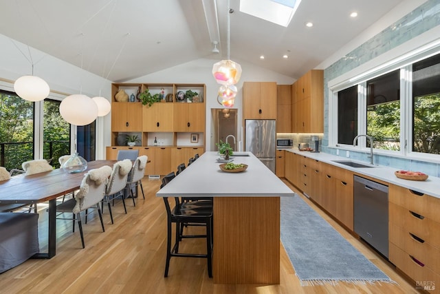 kitchen featuring a center island with sink, pendant lighting, sink, and appliances with stainless steel finishes